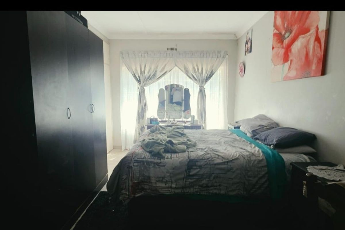 A standard bedroom featuring a built-in wardrobe and large window with natural light, providing a functional space for rest.