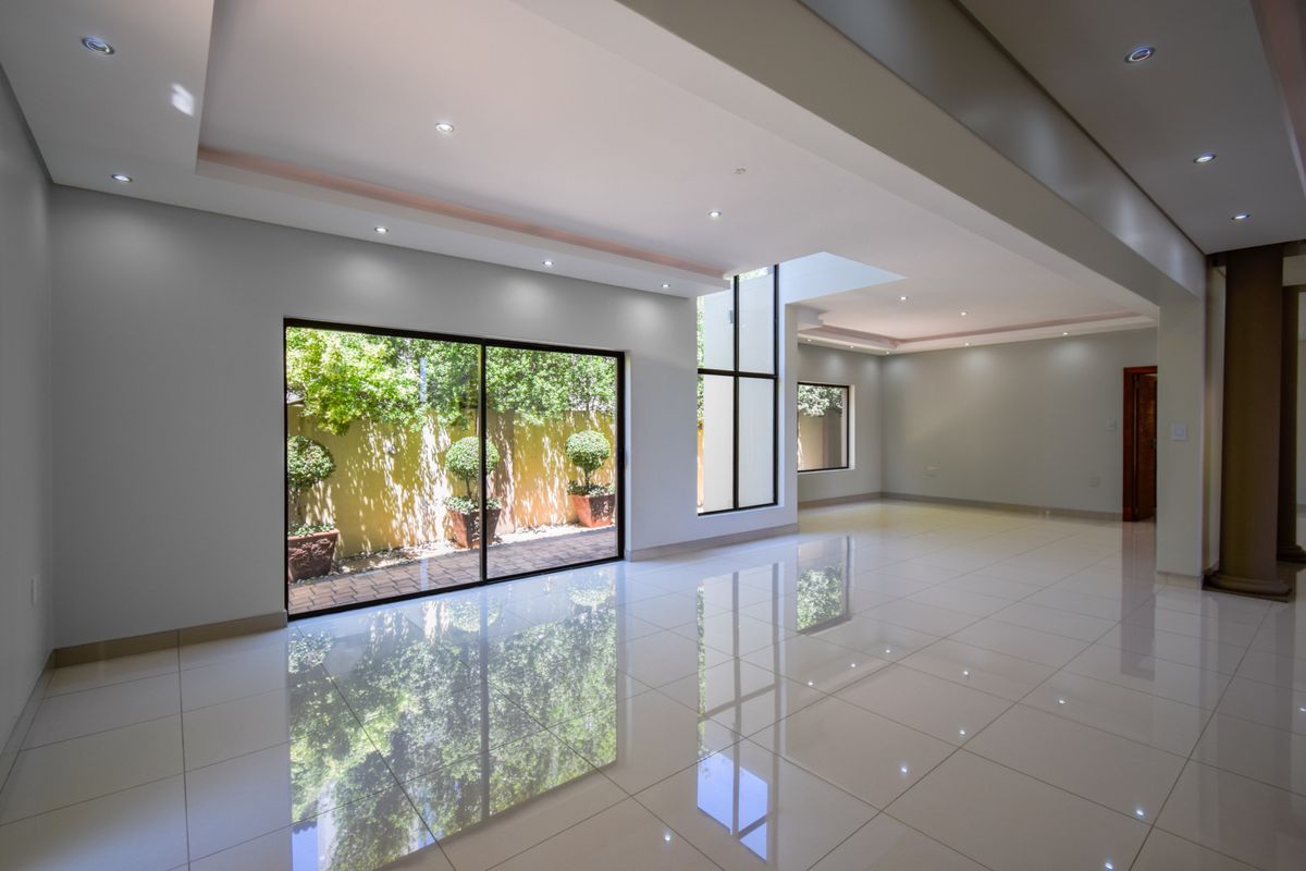 Spacious, light-filled living area featuring polished porcelain floor tiles, recessed ceiling lighting, and large sliding glass doors opening to a private garden courtyard.