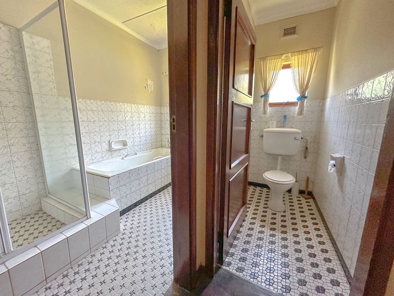 A dated bathroom featuring a separate shower enclosure, built-in bathtub, and toilet with classic ceramic tiling throughout.