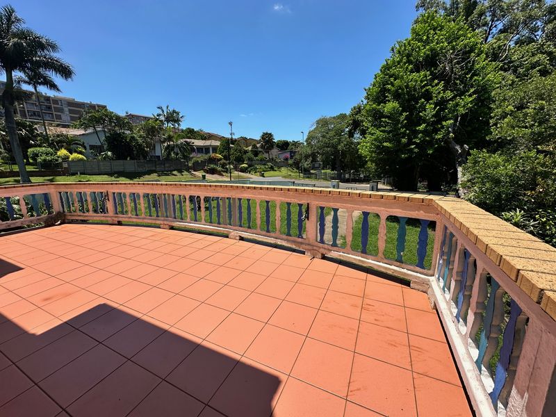 Spacious outdoor balcony featuring tiled flooring and a classic concrete balustrade with brick capping, offering an open view of the surrounding neighbourhood.
