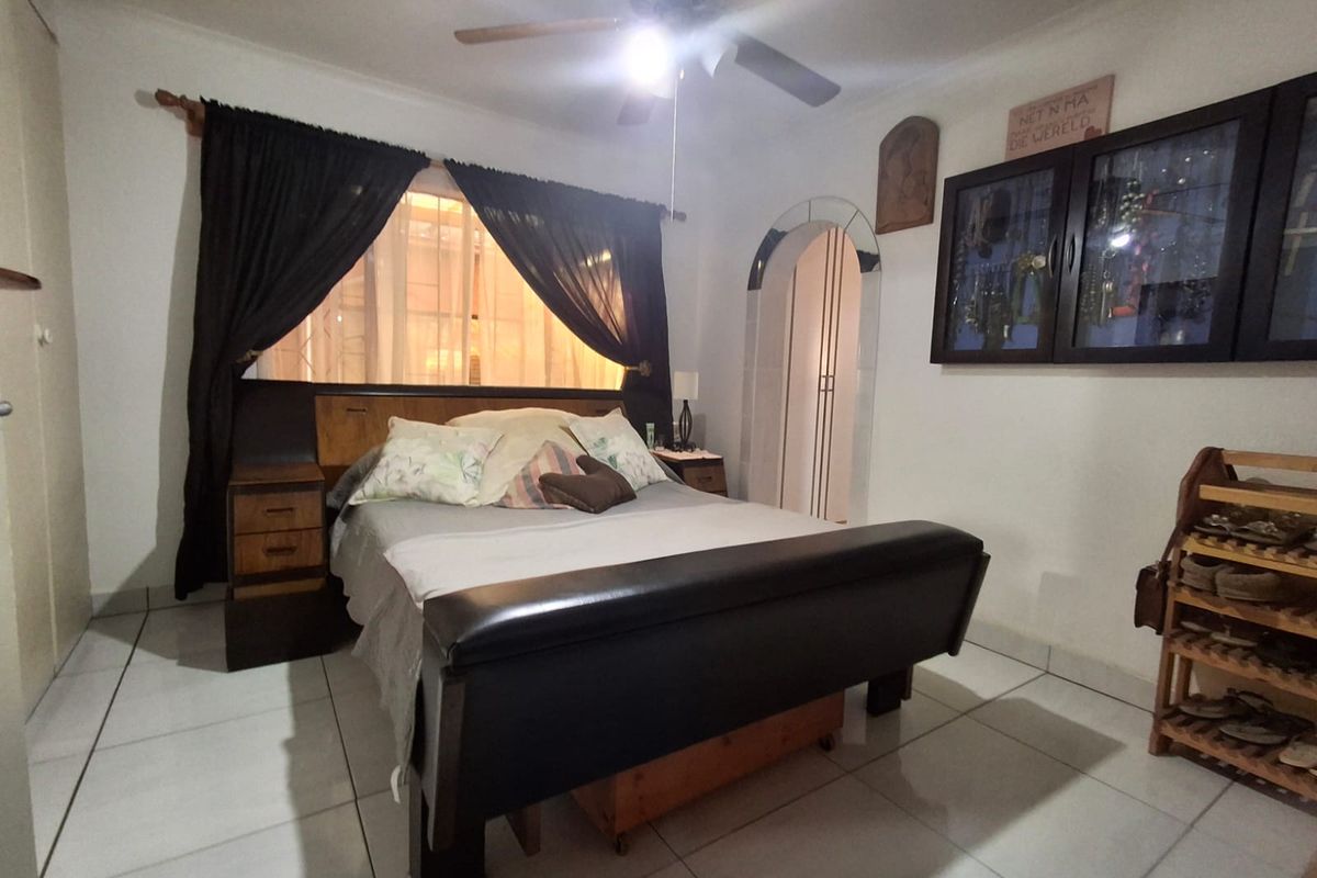 A bedroom featuring tiled flooring, a ceiling fan, and an arched doorway leading to an adjacent space.