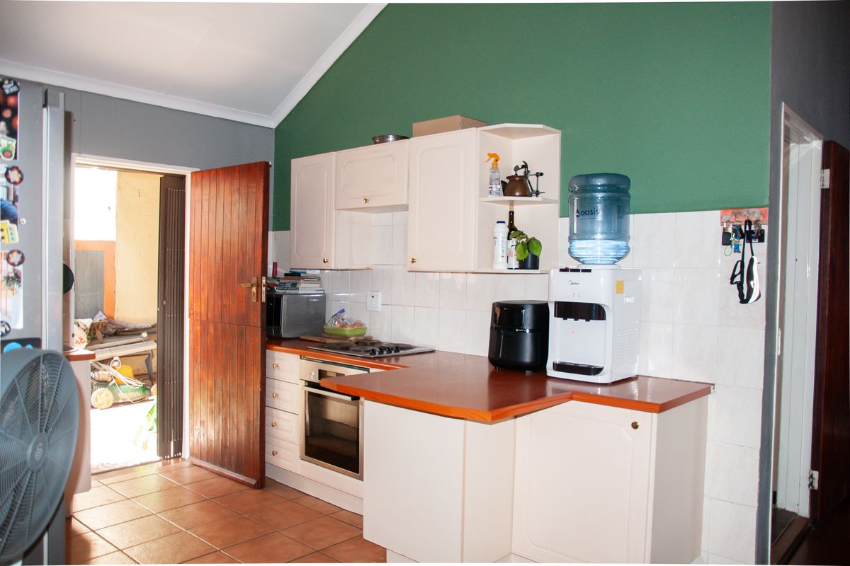A functional kitchen featuring built-in cabinetry, a fitted oven and hob, tiled splashbacks, and direct access to an outdoor area.