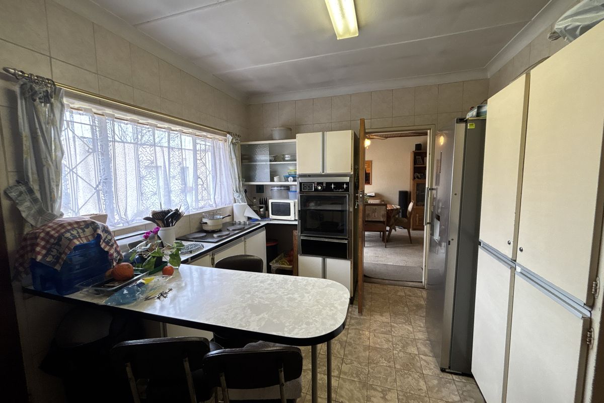 A dated kitchen featuring built-in cabinetry, an integrated oven, tiled splashbacks, and a breakfast nook, offering significant potential for modernization.