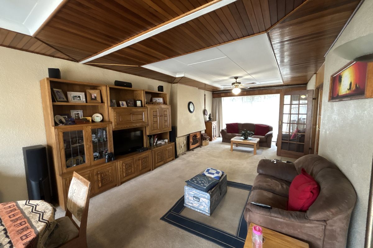 Spacious living room featuring a distinctive timber-clad ceiling, a central fireplace, and glass-paneled french doors leading to an adjacent area.