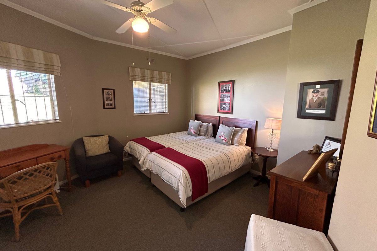A well-maintained bedroom featuring neutral wall tones, carpeted flooring, and a ceiling fan, providing a comfortable and functional living space.