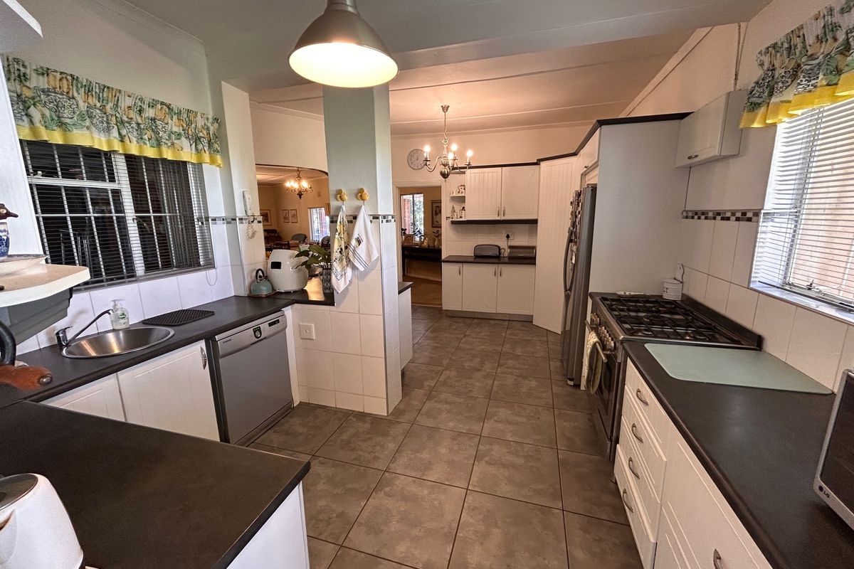 A functional kitchen featuring tiled flooring, white cabinetry, dark countertops, and a gas stove, with an open-plan layout connecting to the living area.