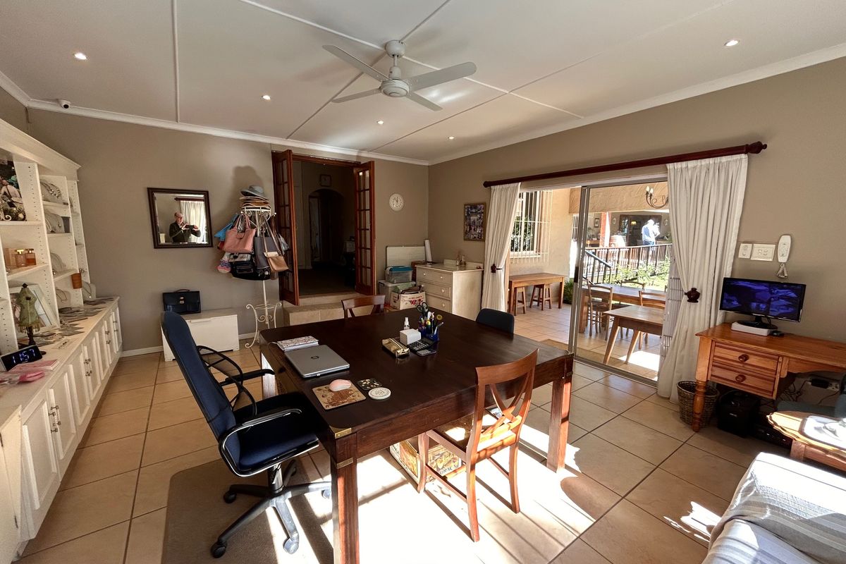 Spacious living area featuring tiled flooring, built-in cabinetry, ceiling fan, and sliding glass doors providing direct access to the outdoor patio.