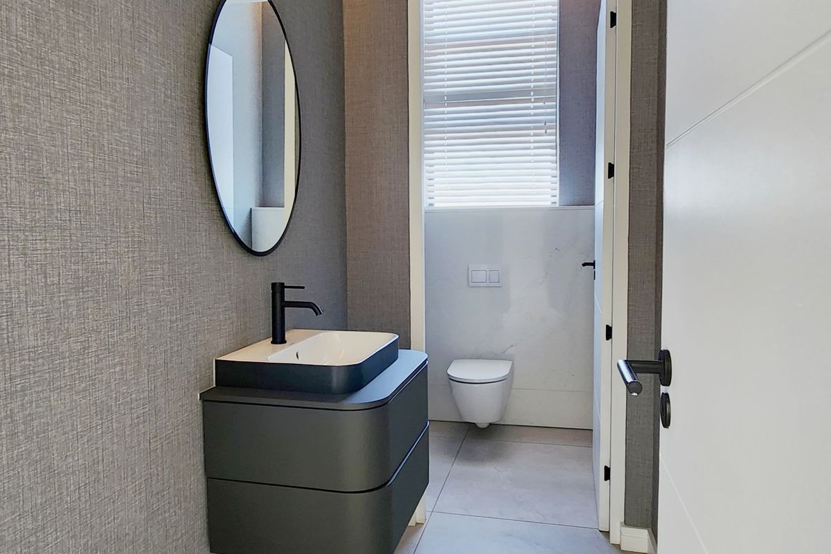 Modern guest bathroom featuring a wall-mounted vanity with a vessel sink, matte black fixtures, and a wall-hung toilet in a separate enclosure.