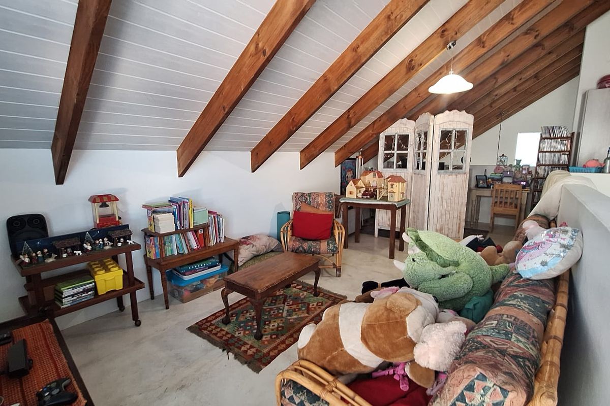 A cozy living area featuring a vaulted ceiling with exposed timber rafters and durable concrete flooring, offering a unique architectural character.