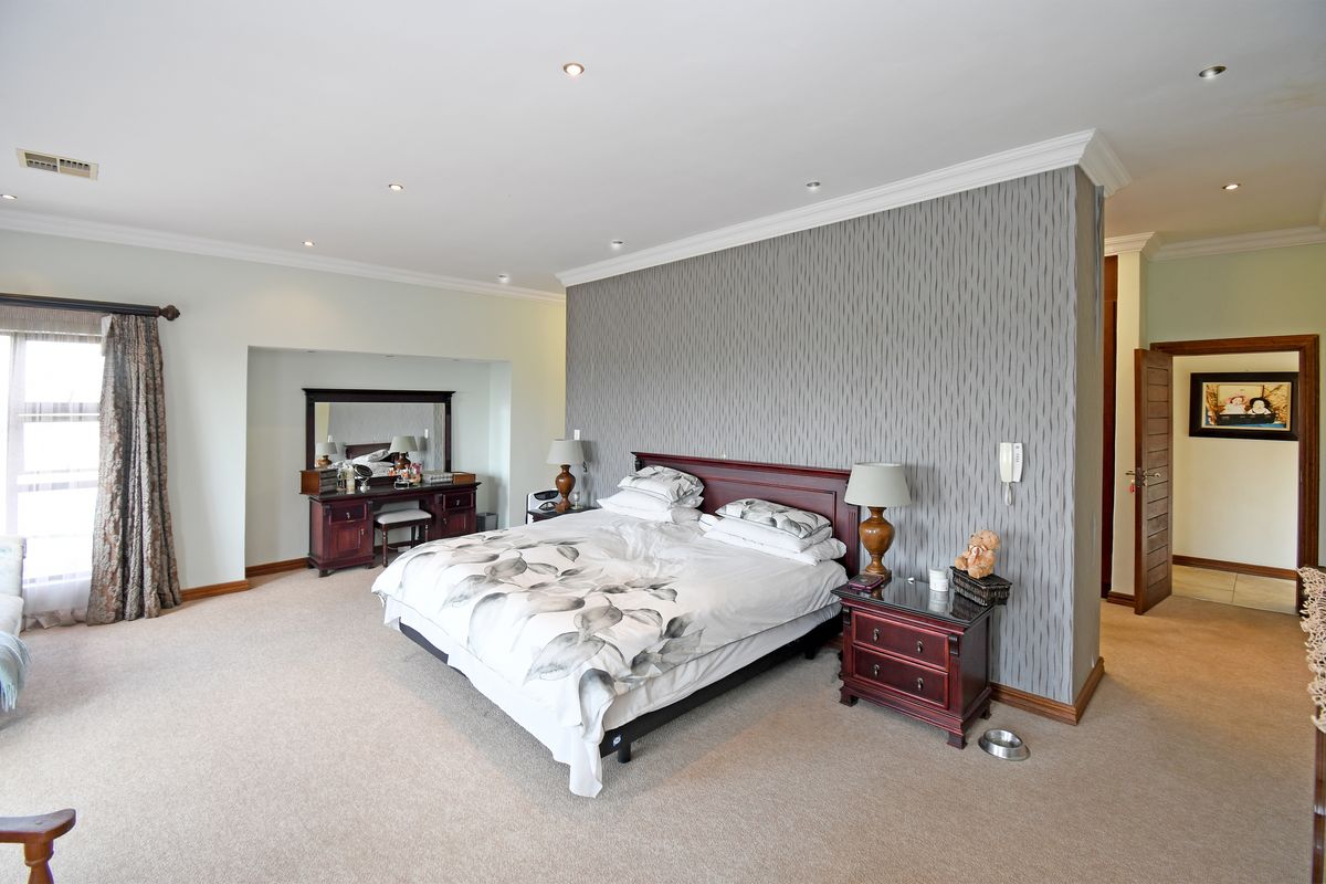 Spacious bedroom featuring a central partition wall with textured wallpaper, recessed downlighting, and neutral carpeting.