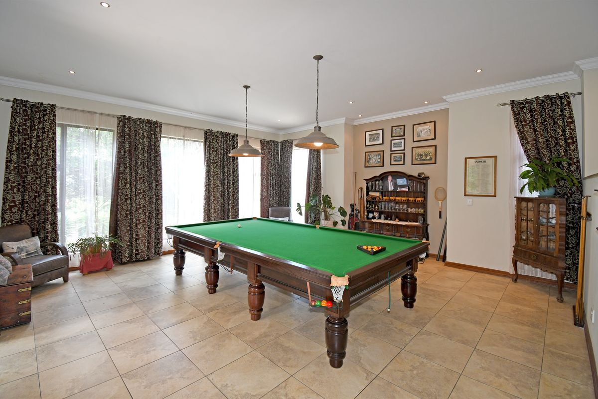 Spacious entertainment room featuring large format floor tiles, recessed downlighting, and expansive windows with floor-to-ceiling curtains.