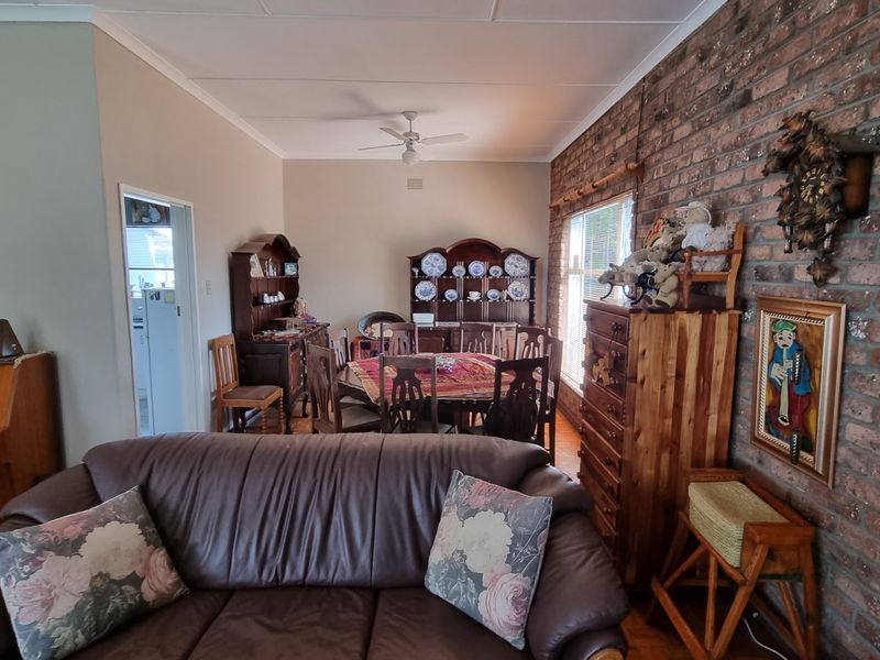 Open plan living and dining area featuring a prominent exposed brick feature wall and ceiling fan.