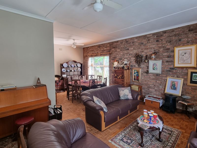 Spacious open-plan living and dining area featuring a characterful exposed brick wall, parquet flooring, and ceiling fans.