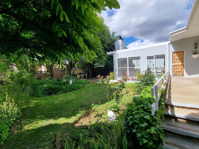 A well-maintained rear garden featuring a covered patio, concrete steps, and a lawn area, providing a pleasant outdoor living space.