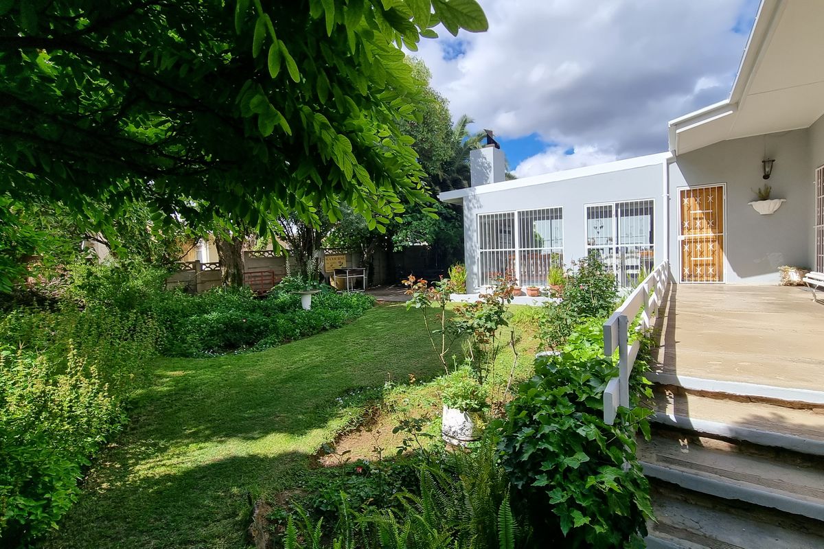 A well-maintained rear garden featuring a covered patio, concrete steps, and a lawn area, providing a pleasant outdoor living space.