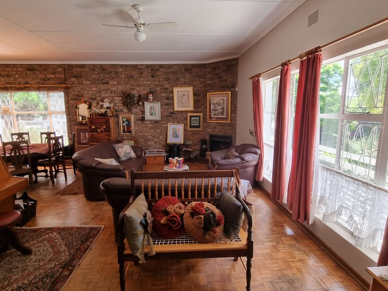 Spacious living room featuring classic parquet flooring, an exposed brick feature wall, a built-in fireplace, and large windows providing ample natural light.