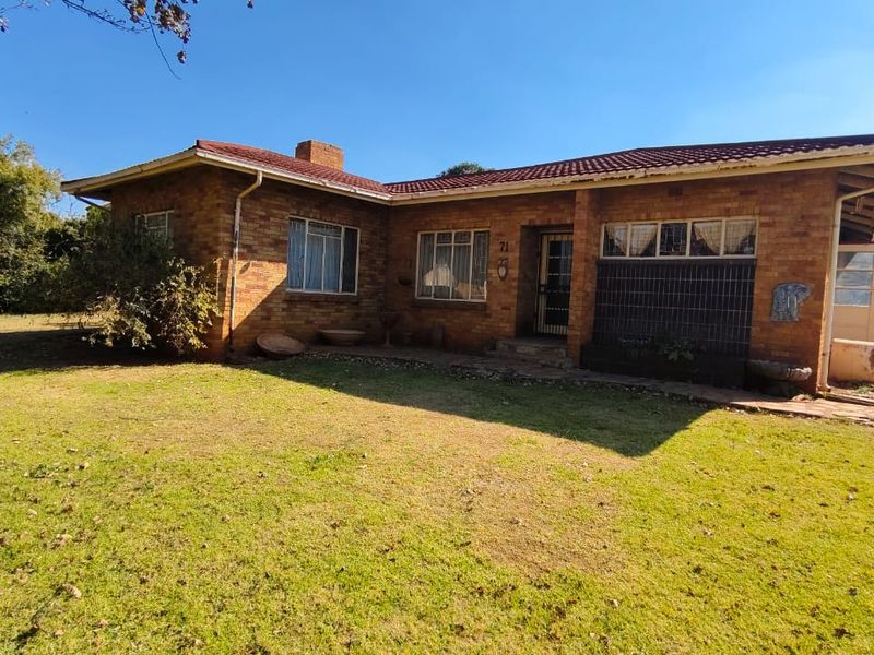 A single-story brick house featuring a traditional tiled roof, front entrance, and a spacious surrounding lawn area.