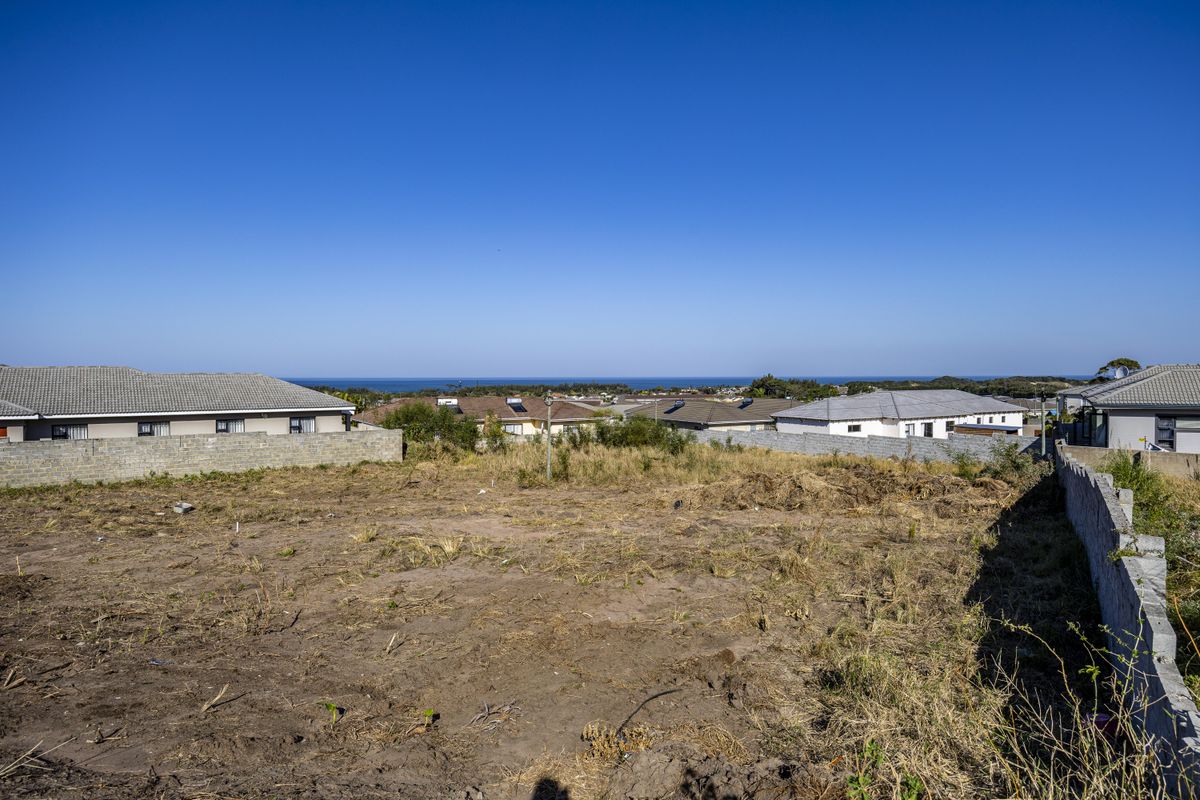A vacant residential plot featuring boundary walls and distant ocean views, offering a blank canvas for new construction.