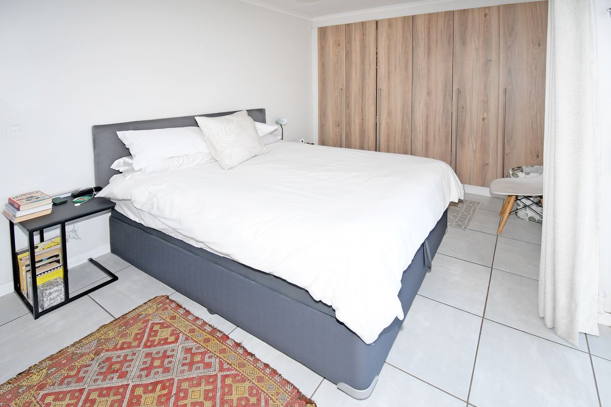 A well-maintained bedroom featuring neutral floor tiles and extensive built-in wooden cabinetry for storage.