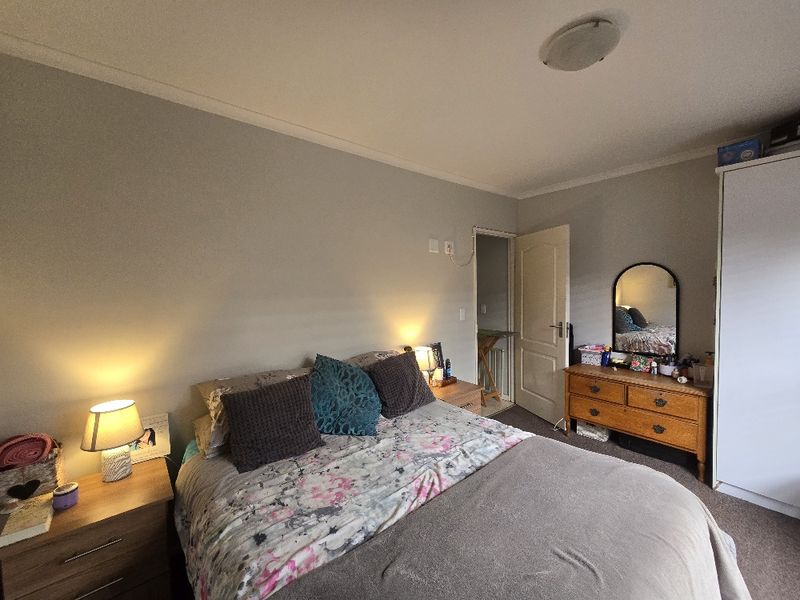 A well-proportioned bedroom featuring neutral wall finishes, a built-in wardrobe, and direct access to an adjoining space.
