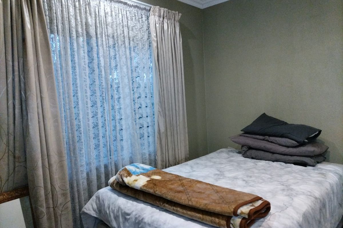 A standard bedroom featuring neutral wall paint, decorative ceiling cornicing, and window treatments.
