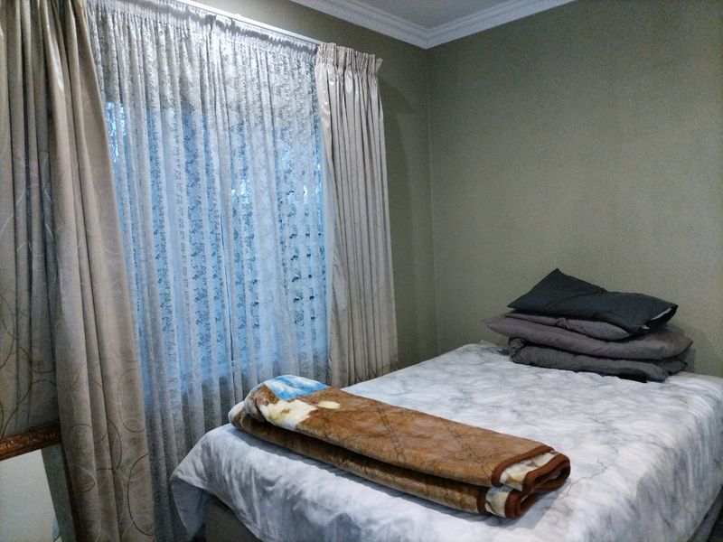 A standard bedroom featuring neutral wall paint, decorative ceiling cornicing, and window treatments.