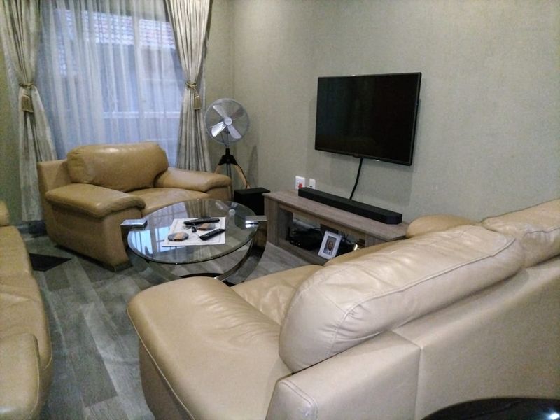 A comfortable living room featuring laminate flooring and a wall-mounted television setup.