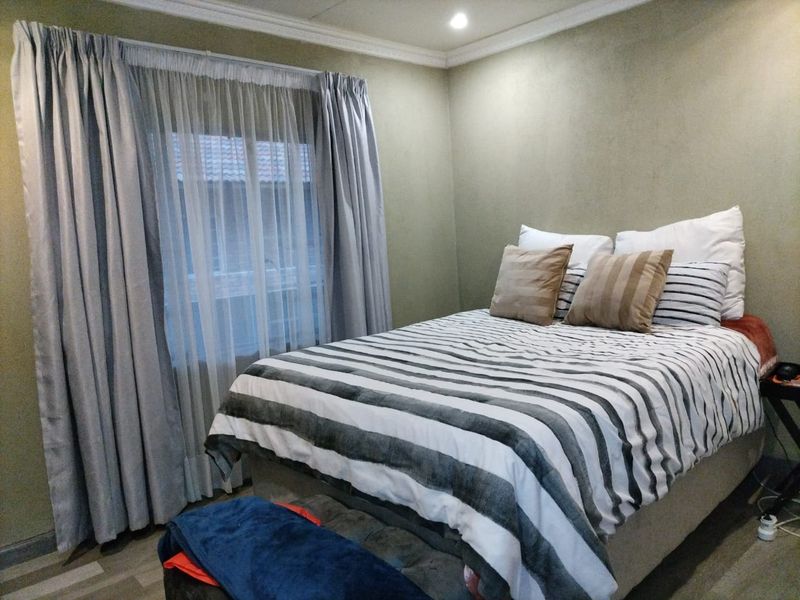 A cozy bedroom featuring neutral wall tones, crown molding, and recessed lighting, providing a comfortable and functional sleeping space.
