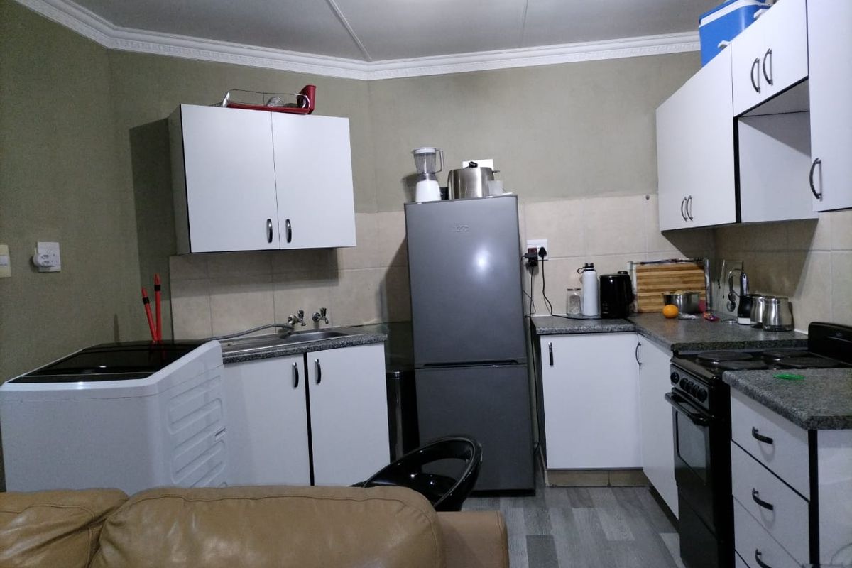 A functional kitchen featuring white cabinetry, laminate countertops, tiled backsplash, and a freestanding stove, with a practical layout for daily meal preparation.