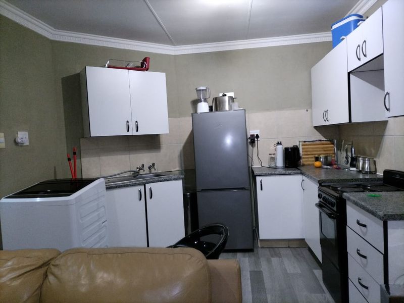 A functional kitchen featuring white cabinetry, laminate countertops, tiled backsplash, and a freestanding stove, with a practical layout for daily meal preparation.