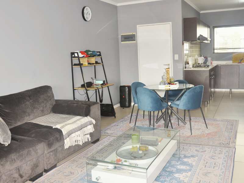 Open-plan living and dining area featuring tiled floors and a modern kitchen with built-in cabinetry, gas hob, and extractor fan.