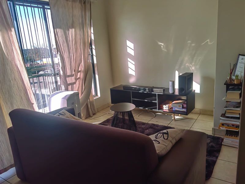 A living room area featuring tiled flooring and a sliding glass door with an integrated security gate, providing access to an outdoor space.