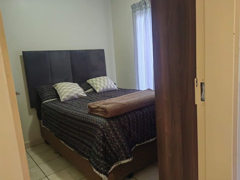 A compact bedroom featuring tiled flooring and a sliding door entrance, providing a functional sleeping space.