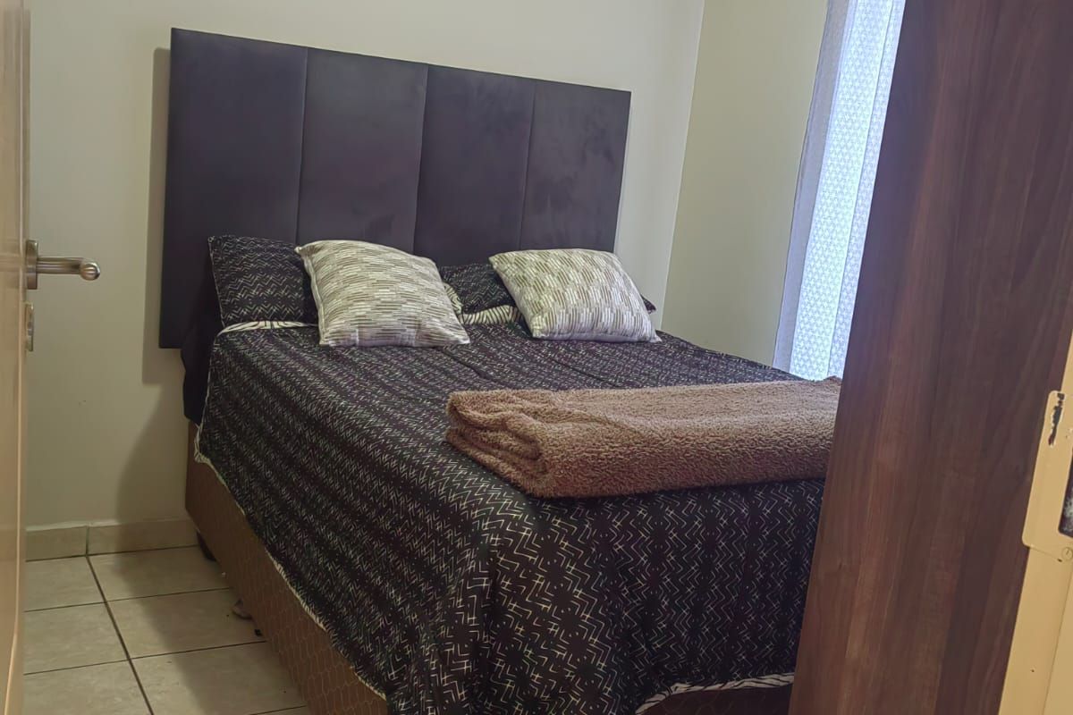 A compact bedroom featuring neutral wall finishes and tiled flooring, providing a functional space with natural light through the window.