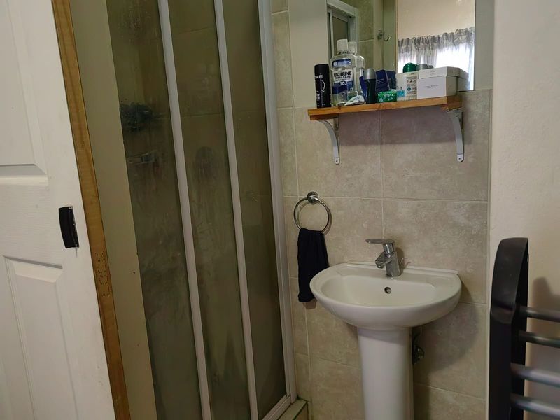 Compact bathroom featuring a pedestal basin, chrome mixer tap, and a shower enclosure with tiled wall finishes.