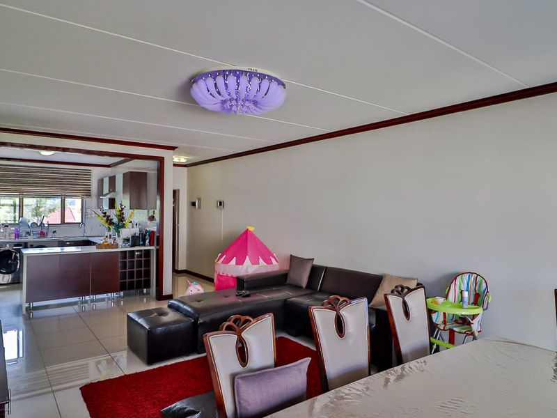 Open plan living and dining area featuring tiled flooring and a connected kitchen with built-in cabinetry.