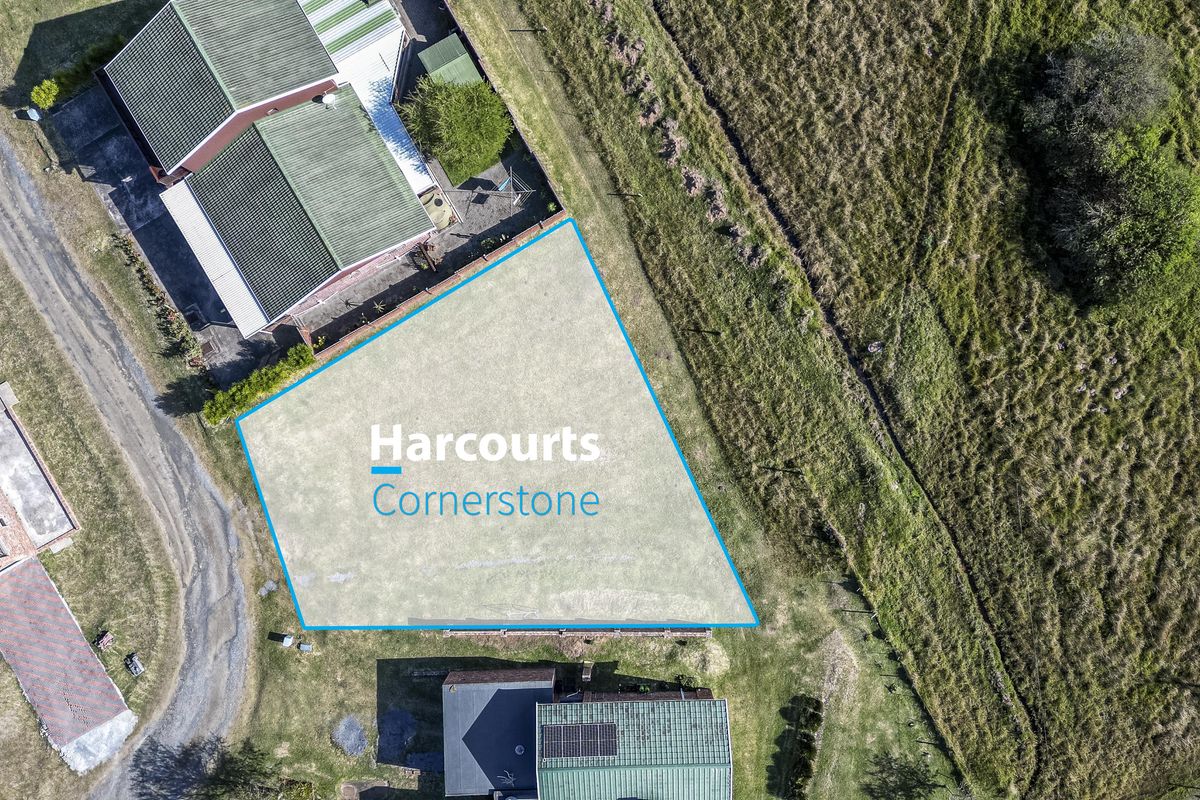 An aerial view of a vacant residential plot, clearly demarcated with boundary lines, situated in a developed neighborhood.