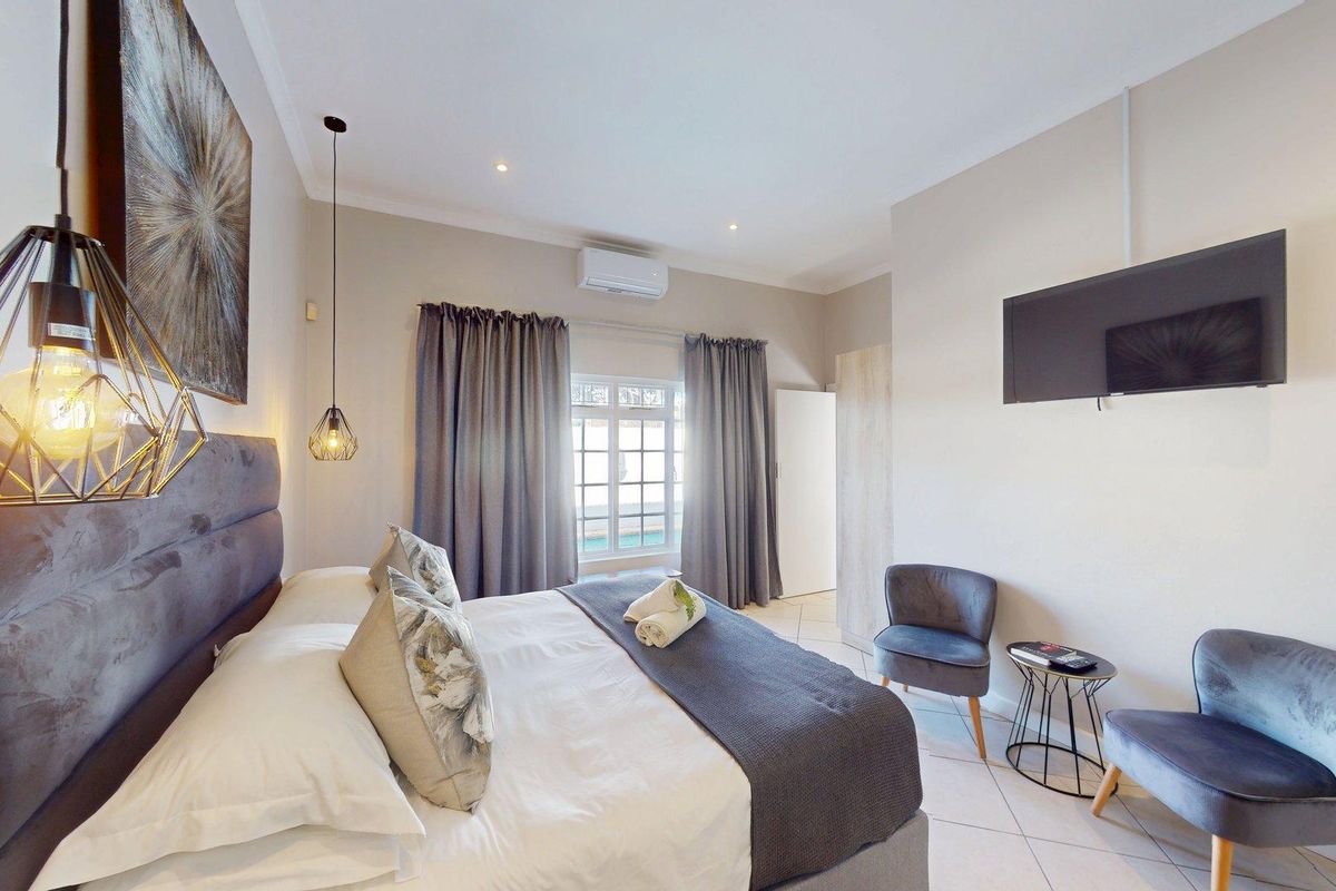 A well-maintained bedroom featuring tiled flooring, a split-system air conditioner, recessed lighting, and a built-in cupboard.