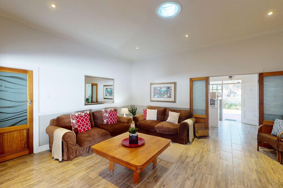 A bright living room featuring tiled flooring, recessed lighting, a skylight, and wooden doors leading to an adjacent space.