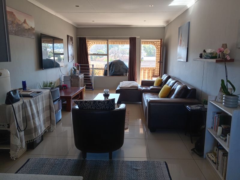 A comfortable living room featuring tiled flooring, recessed lighting, and direct access to an outdoor patio area through a sliding door.
