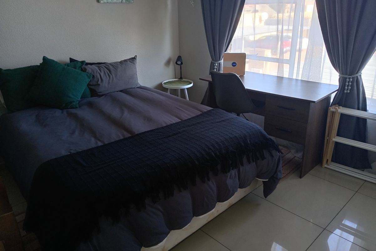A functional bedroom featuring tiled flooring and a large window that allows for natural light.