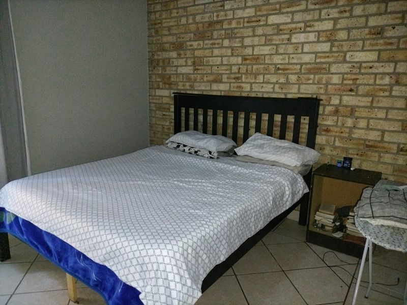 A bedroom featuring an exposed brick feature wall and tiled flooring.