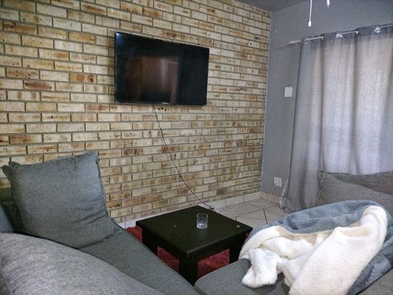 Living room featuring an exposed brick feature wall and neutral ceramic floor tiles.
