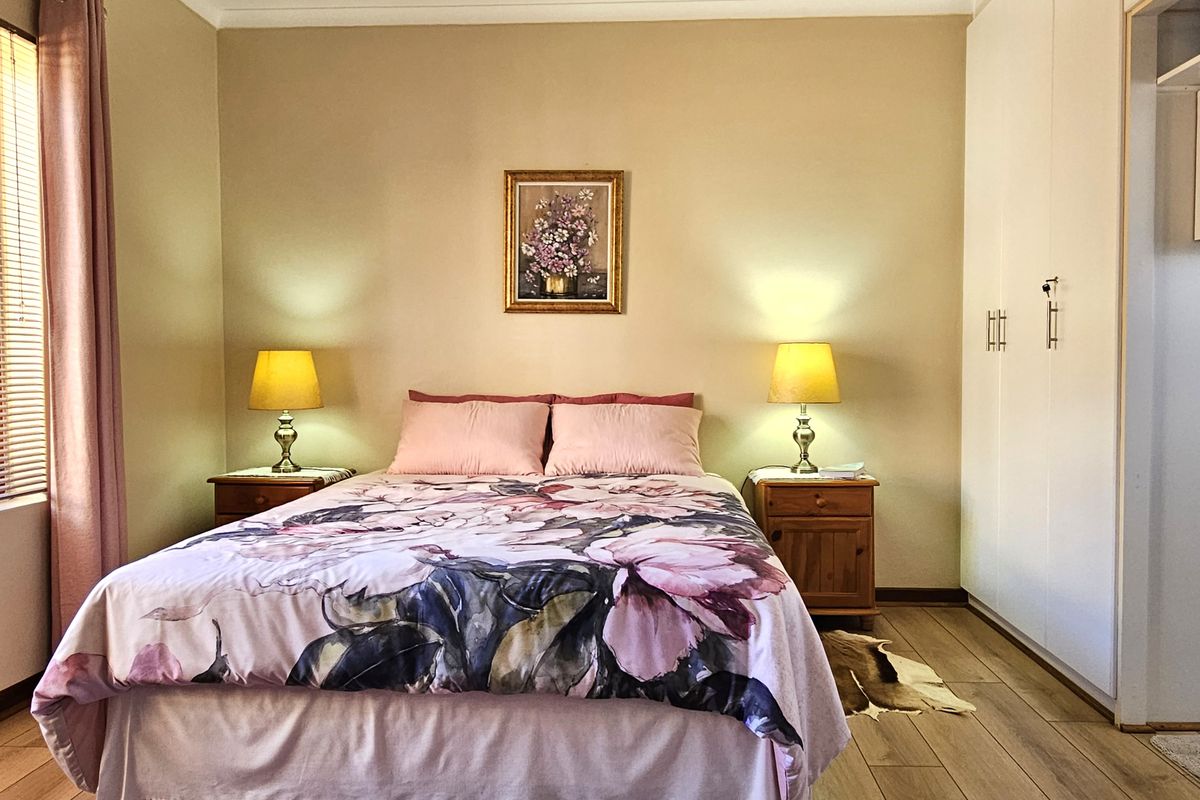 A well-maintained bedroom featuring laminate flooring, neutral wall finishes, and ample built-in cupboard storage.