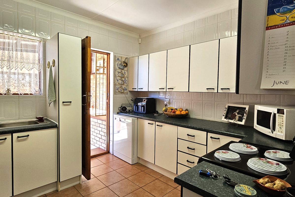 A functional kitchen featuring white cabinetry, dark laminate countertops, tiled backsplash, and direct access to an outdoor area.