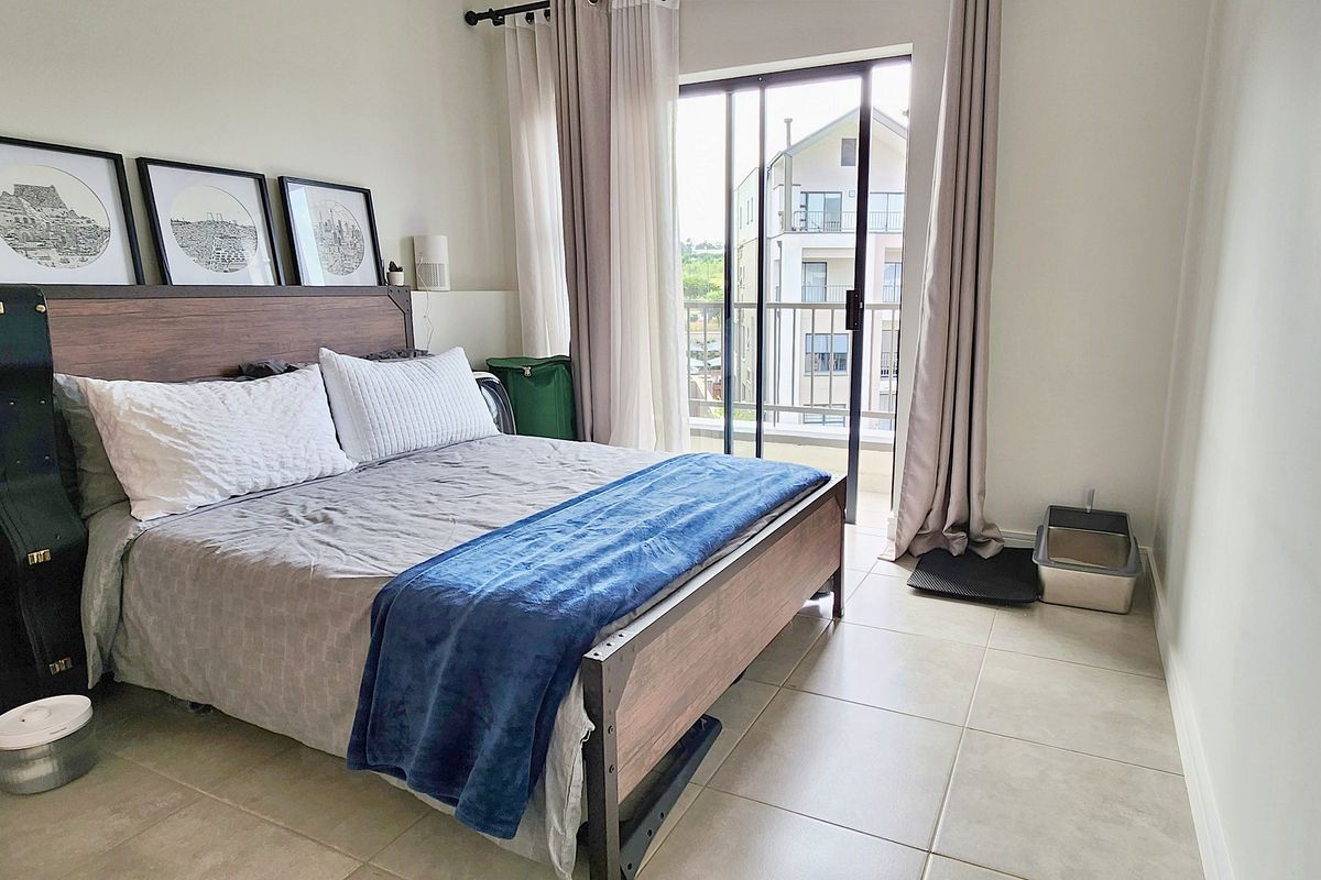A well-lit bedroom featuring tiled flooring and a sliding glass door that opens onto a private balcony.