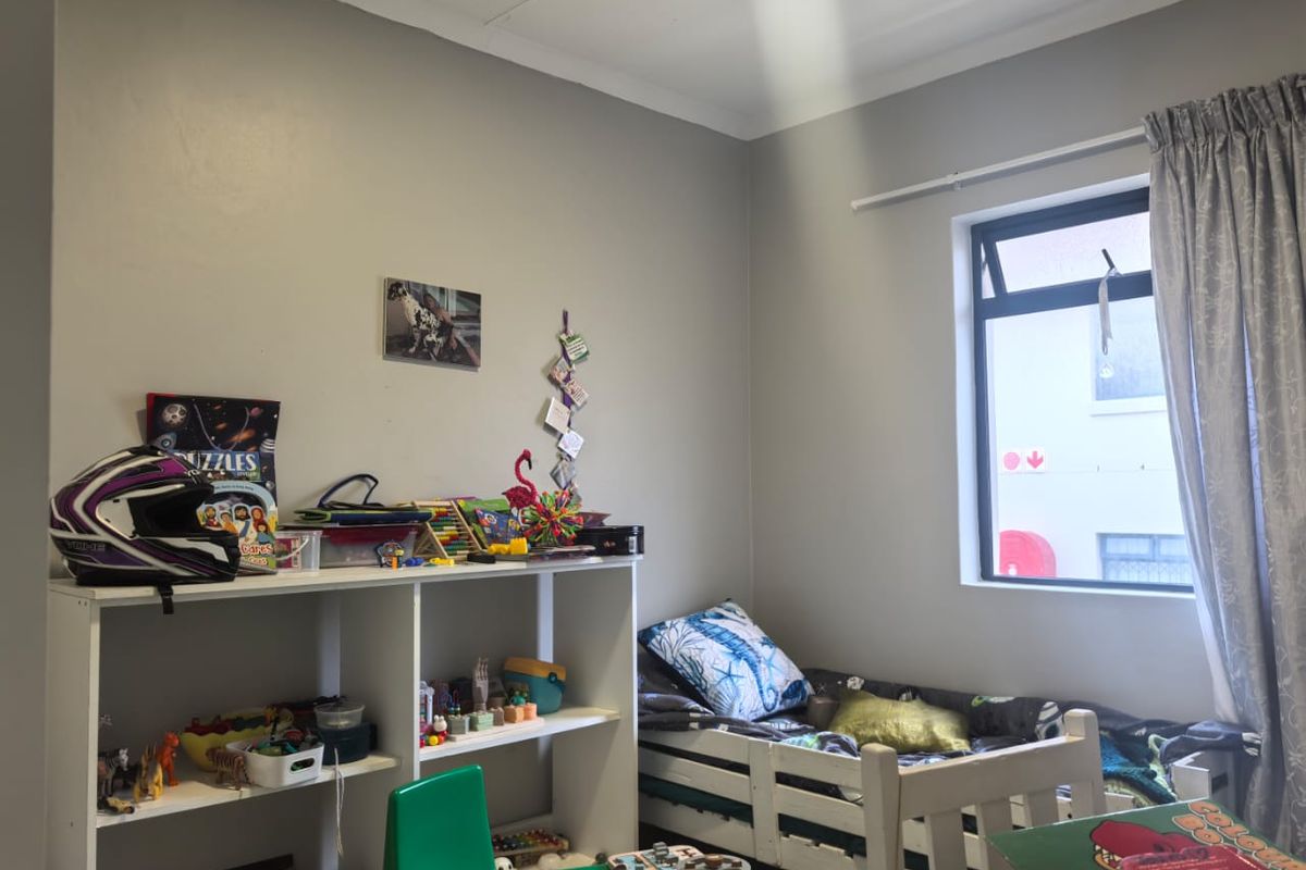 A bedroom featuring a top-hung window with curtain track and neutral wall finishes, suitable for a child's room or guest space.