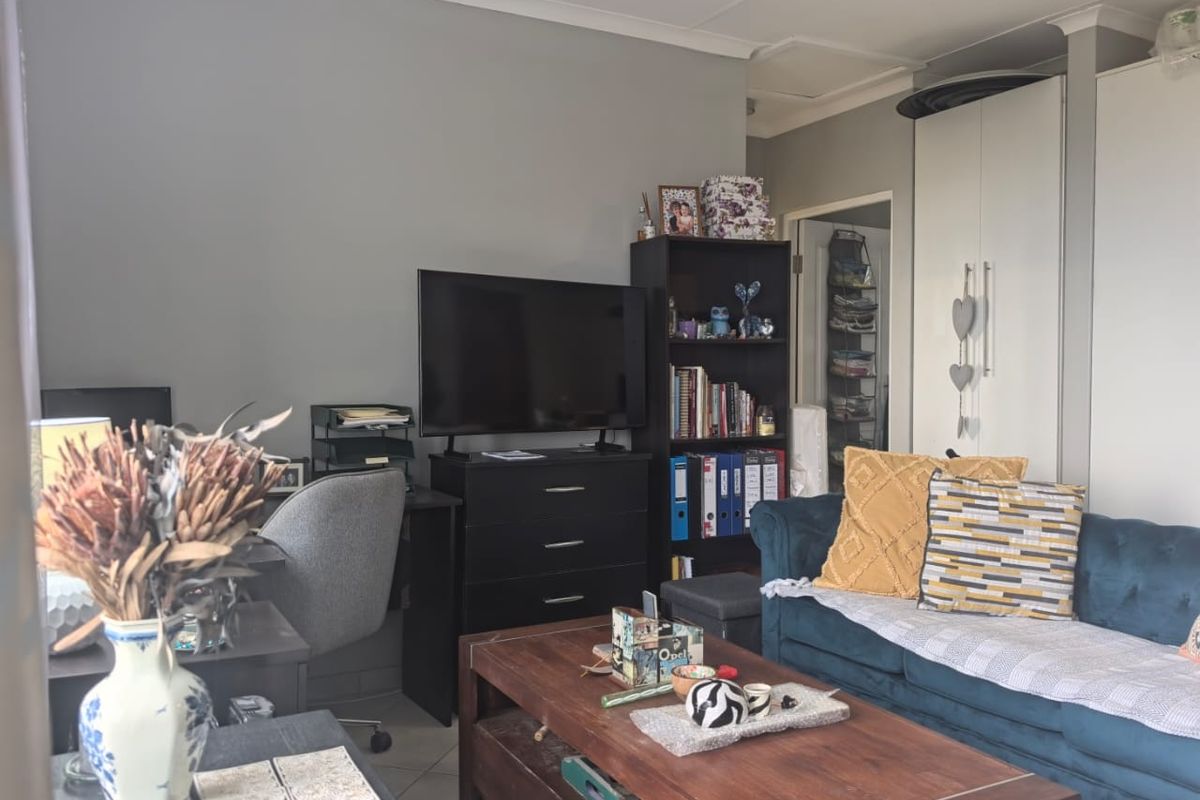 A living room featuring tiled flooring, coved ceilings, and built-in storage cupboards, providing a functional and comfortable living space.