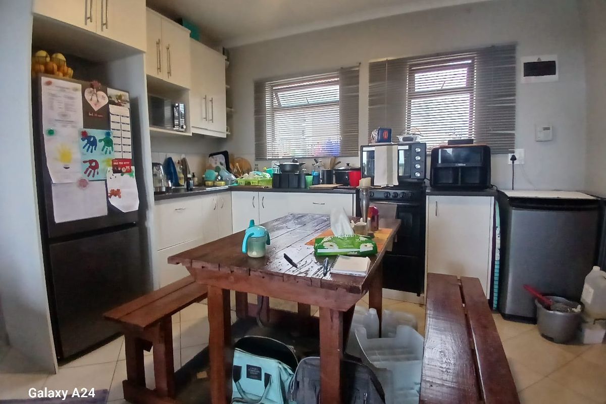 A functional kitchen featuring white cabinetry, tiled flooring, and dual windows with venetian blinds, providing a practical workspace for daily meal preparation.