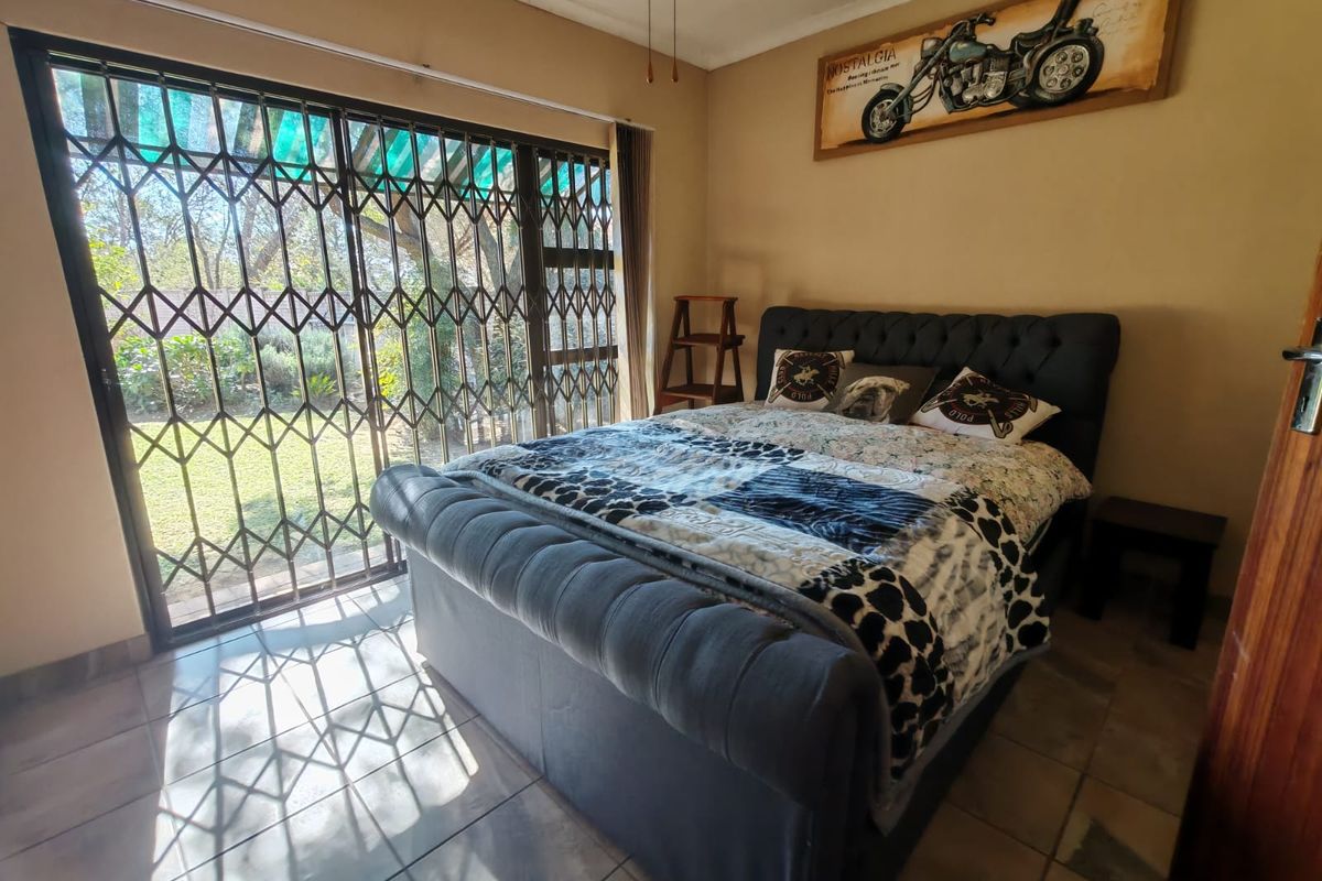 Bedroom featuring tiled flooring and a large sliding glass door with security gate, providing direct access to the garden area.